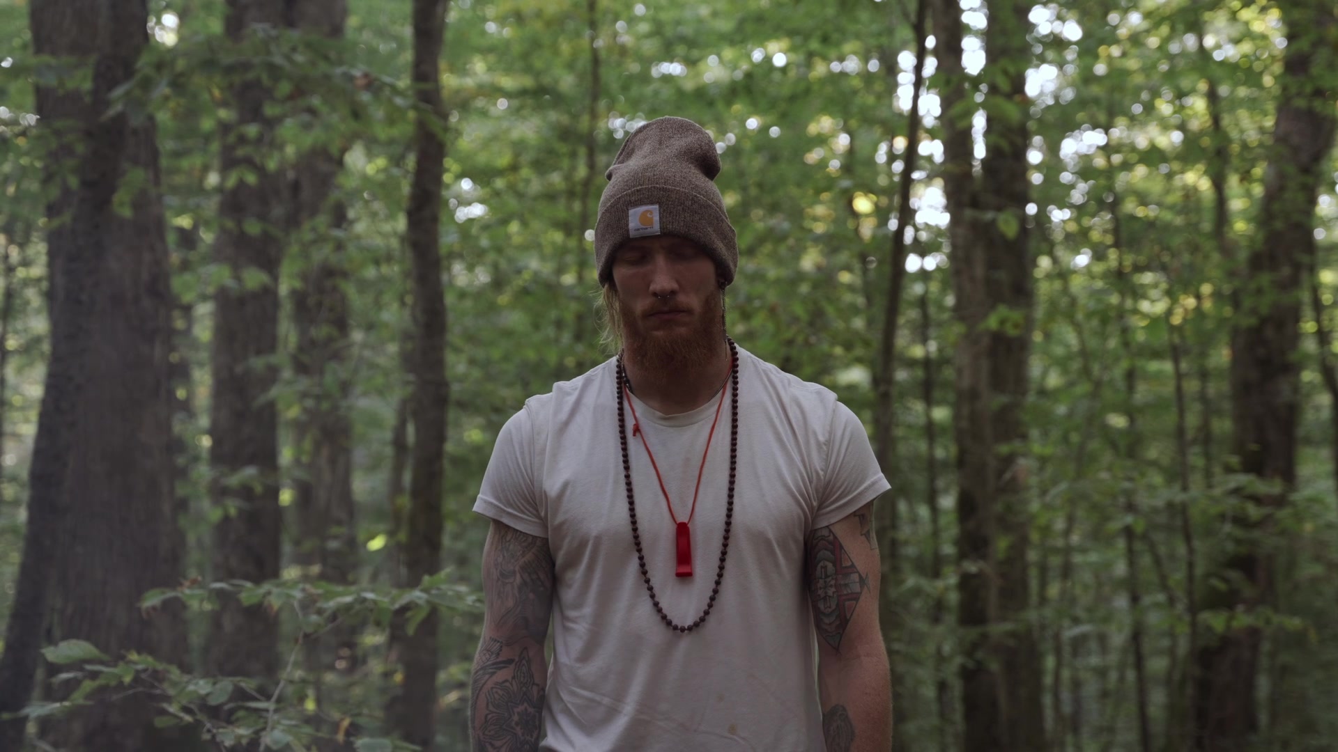 Erik in a white t-shirt and beanie in the forest
